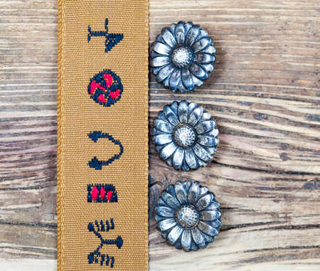 vintage tape with embroidered ornaments and old buttons flowers on a textured surface aged boardsの写真素材