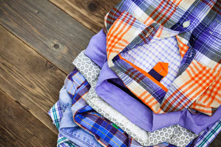 stack of colored shirts on a wooden shelf in a clothes store