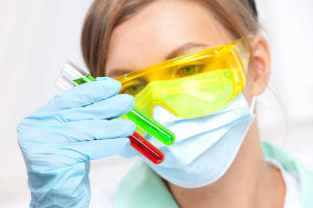 woman doctor in a mask examines test tubes