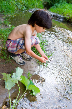 boy near the stream starts boatの写真素材
