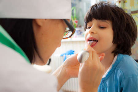 children's doctor otolaryngologist looking boy throatの写真素材