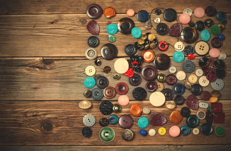 Old buttons on the wooden boards of the antique table. Collection of antique buttonsの写真素材