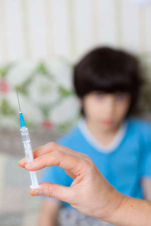 Doctor hand with syringe and child on the backgroundの写真素材