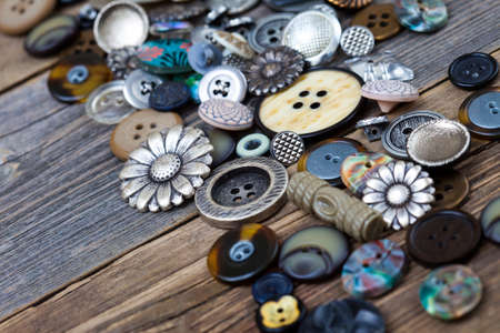 Vintage buttons in large numbers scattered on aged wooden boards of old deskの写真素材