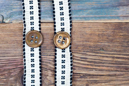 Vintage tape with embroidered pattern and ancient classical buttons on the old textured boardsの写真素材