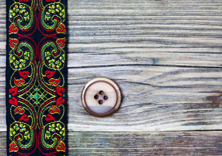 old band with embroidered ornaments and vintage button on a textured surface aged boardsの写真素材