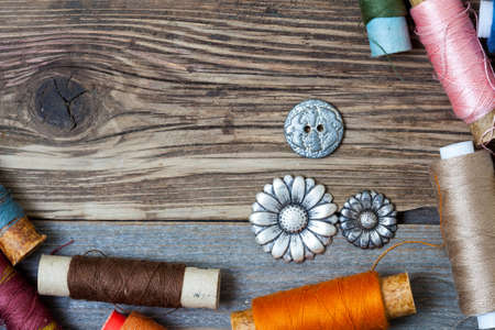 spool of thread and buttons on a vintage aged textured boards