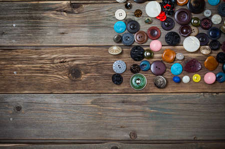 Set of antique and modern stylish buttons for clothes on an old textured wooden surface, still life