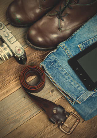 set of traveler with a digitizer, leather belt, rangefinder camera, jeans and boots on old boards of...