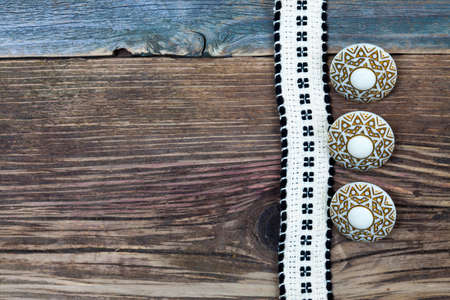 Vintage tape with embroidered pattern and three ancient buttons on the old textured boardsの写真素材