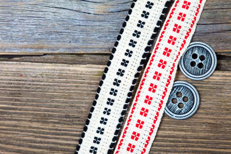 antique ribbons with embroidered ornaments and old buttons on a textured surface aged boards