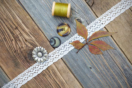 taylor still life with lace tape, vintage buttons, spools of thread and herbarium on the surface of an aged wooden boardsの写真素材