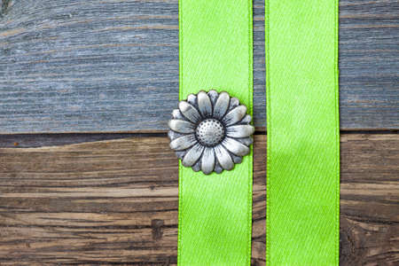 Vintage metallic button flower and two green tape on aged wooden surfaceの写真素材