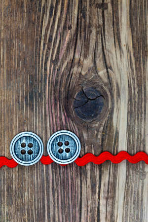 old red tape and two vintage classic buttons on a textured surface aged boardsの写真素材