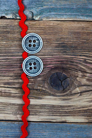 vintage red tape and two old classic buttons on a textured surface aged boardsの写真素材