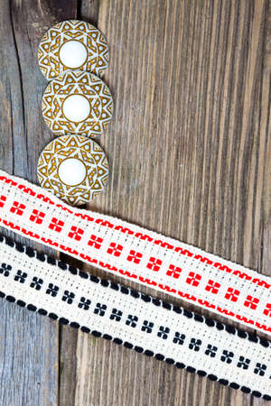 three vintage buttons and two old bands with embroidered ornaments on a textured surface aged boards