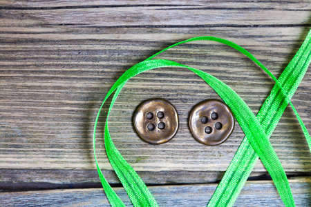 still life with old green tape and two vintage buttons on a textured surface aged boards