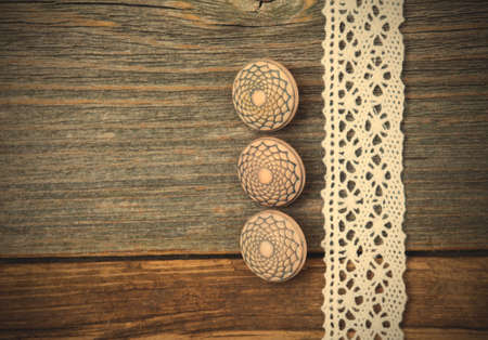 set of three vintage buttons and lace ribbon on the aged wooden surface. instagram image retro styleの写真素材