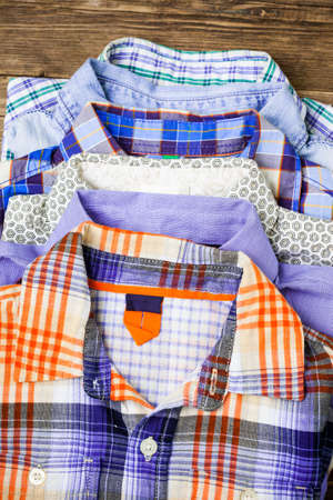 stack of colored children shirts on a wooden shelf in a clothes store