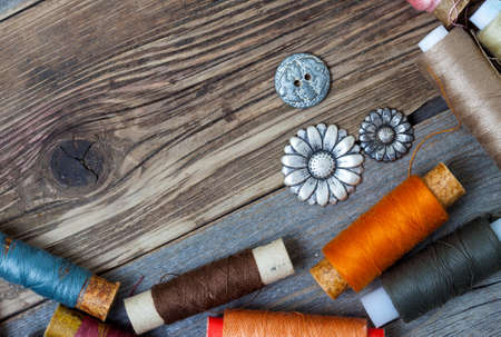 vintage buttons and threed on the textured surface of the ancient tailor's table