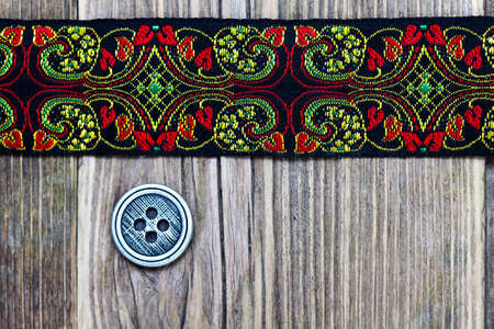 old band with embroidered ornaments and vintage button on a textured surface aged boards