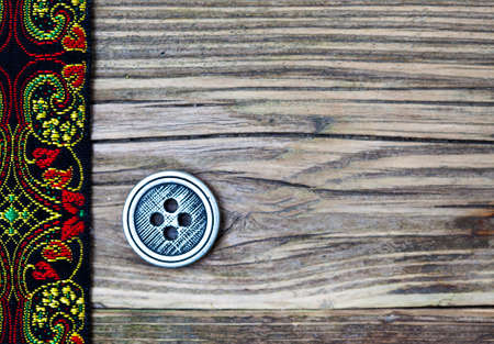 old band with embroidered ornaments and vintage button on a textured surface aged boardsの写真素材