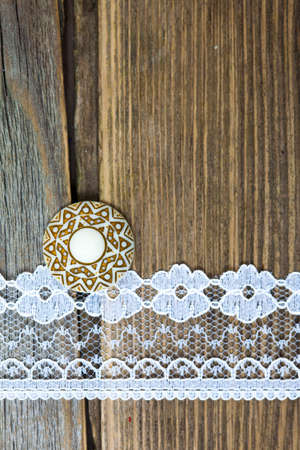 one vintage button and lace tape on old wooden surfaceの写真素材