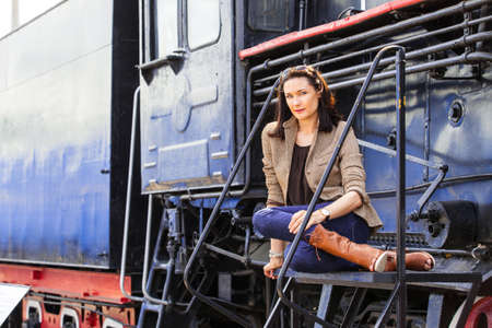 beautiful middle-aged woman near an old steam locomotive. retro trip