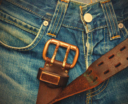 Vintage leather belt with metal buckle on old blue jeans.