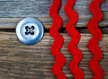 vintage button and old three red tape on a textured surface aged boards