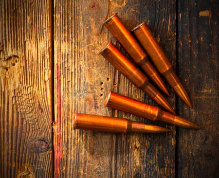 several rifle cartridges on vintage wooden surface.の写真素材