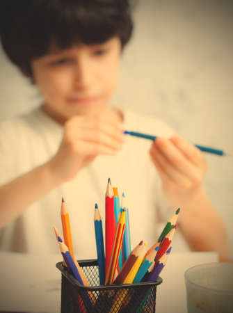 pencil holders with pencil in focus. boy chooses a pencil for drawing on the background.の写真素材