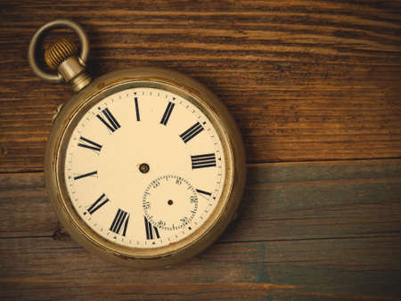 broken vintage watch without hands on the wooden surface.