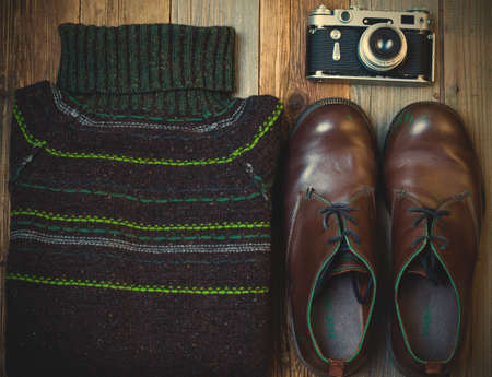 Vintage wool sweater, shoes, antique rangefinder camera on old rough boards. still life in retro...