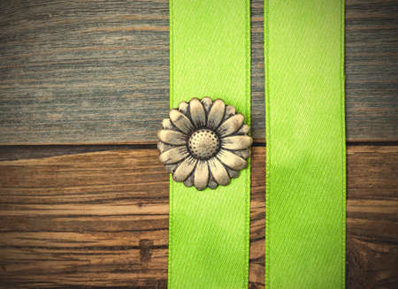 Vintage metallic button flower and two green tape on aged wooden surface.の写真素材