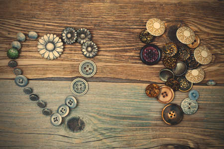 vintage buttons heart and buttons pile on old textured boards of ancient tailor table.の写真素材