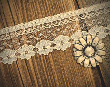vintage button and lace tape on old wooden surface.