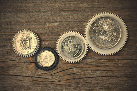 Gears with coins inside on old boards.の写真素材