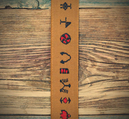 still life, vintage brown tape with embroidered ornaments on a textured surface aged boards.の写真素材