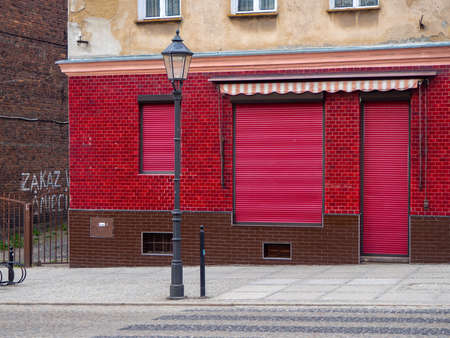 Zgorzelec, Poland-April 10, 2019: Red facade of a closed store with shutters rolled down. Shop located in old part of Zgorzelec, near Nysa river.のeditorial素材