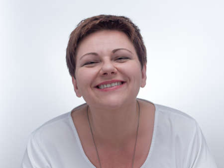Portrait of a smiling caucasian woman with short brown hair. Natural and joyful chubby girl against white background.の写真素材