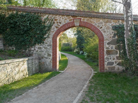 Brick archway in Ochsenzwinger park in Goerlitz. View on path and gate in a warm evening light. Alley in the park located on city walls.の写真素材