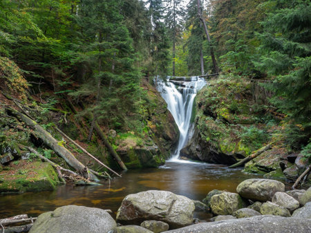 Autumn view of Szklarka Waterfall in Karkonosze Giant Mountains. Long exposure shot of brisk river surrounded with green forest.の写真素材