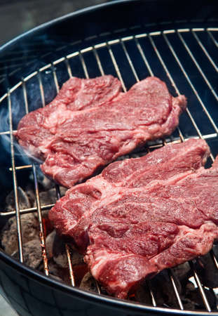 Two beef steaks on charcoal grill with smokeの写真素材