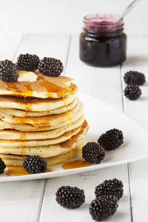 Stack of old-fashioned american pancakes with blackberry and maple syrupの写真素材