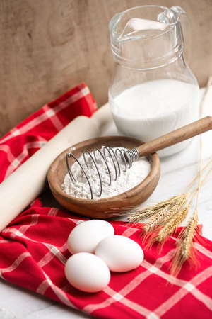 Baking ingredients: eggs,flour,milk on vibrant red towel