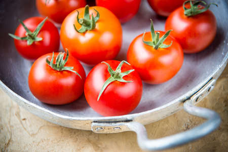 Crop of young tomatoes in a metal skillet, rustic styleの写真素材