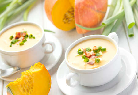 Creamy pumpkin bacon soup in two white bowls, autumn cuisineの写真素材