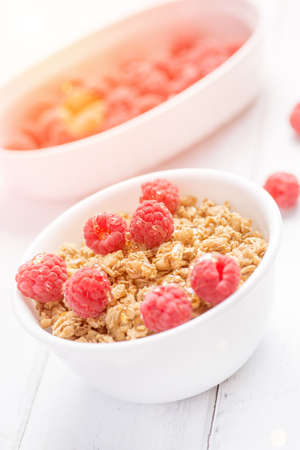 Fresh granola breakfast with raspberries and honey on white rustic tableの写真素材