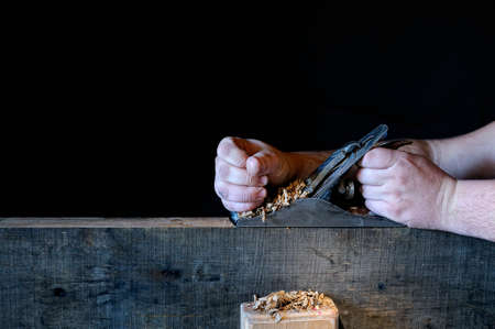 Carpenter working with a planer on black background の写真素材